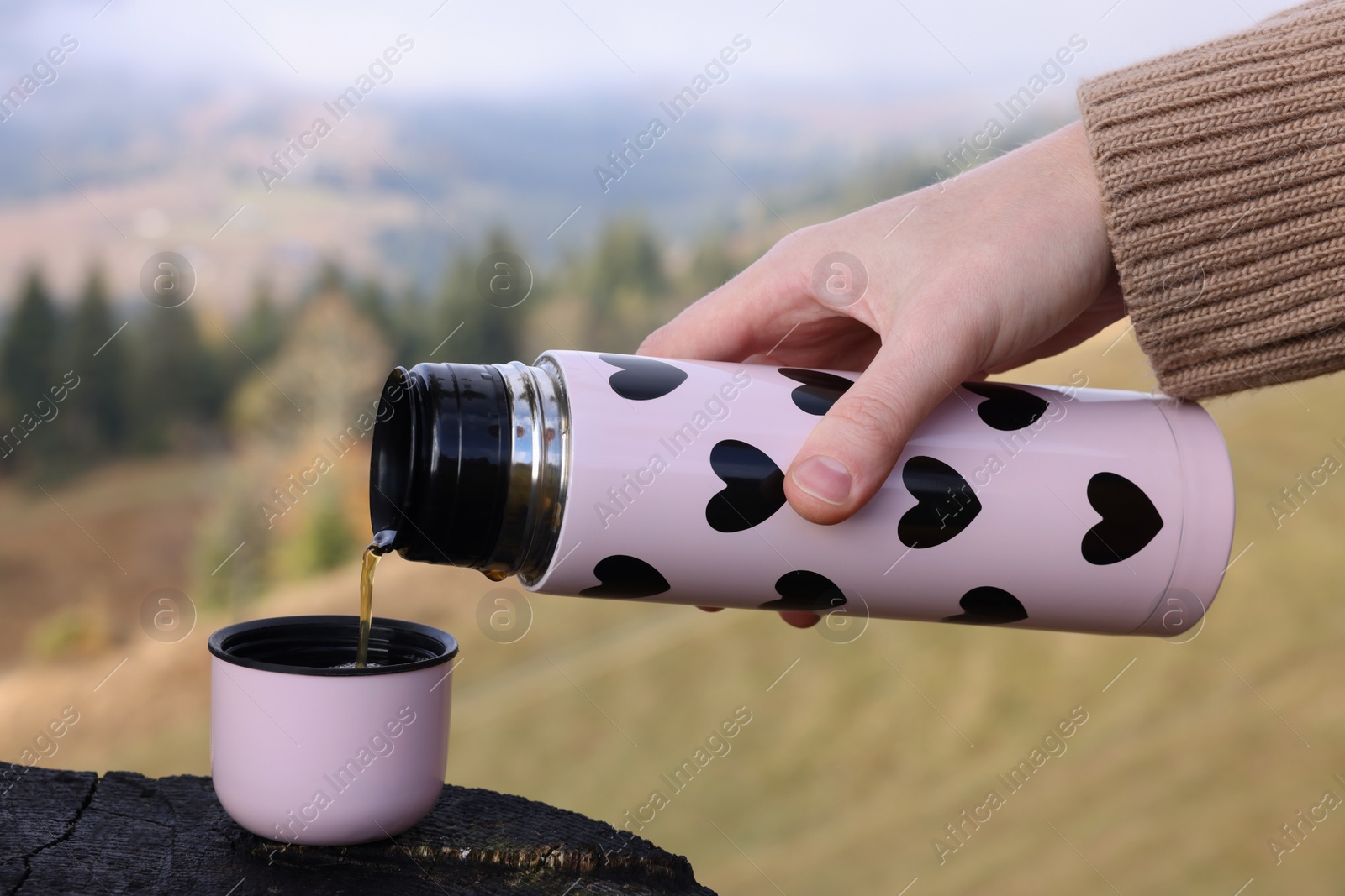 Photo of Woman pouring hot instant coffee in mountains, closeup