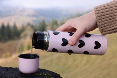 Photo of Woman pouring hot instant coffee in mountains, closeup