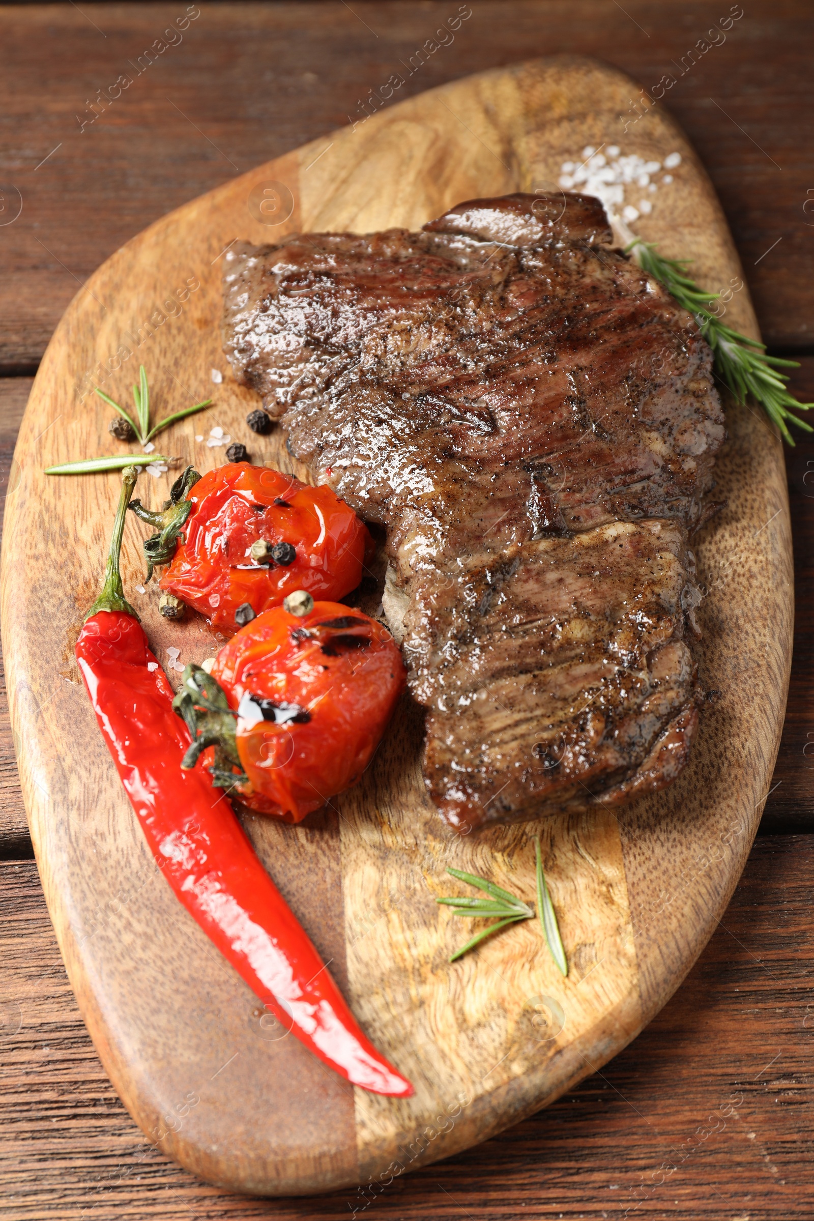 Photo of Delicious roasted beef meat, vegetables and spices on wooden table