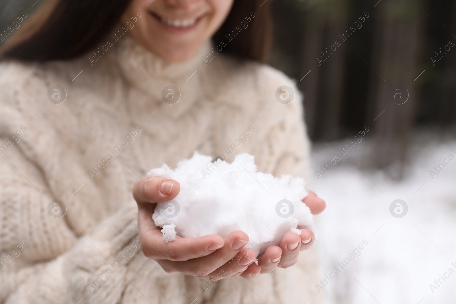 Photo of Young woman holding pile of snow in hands, closeup