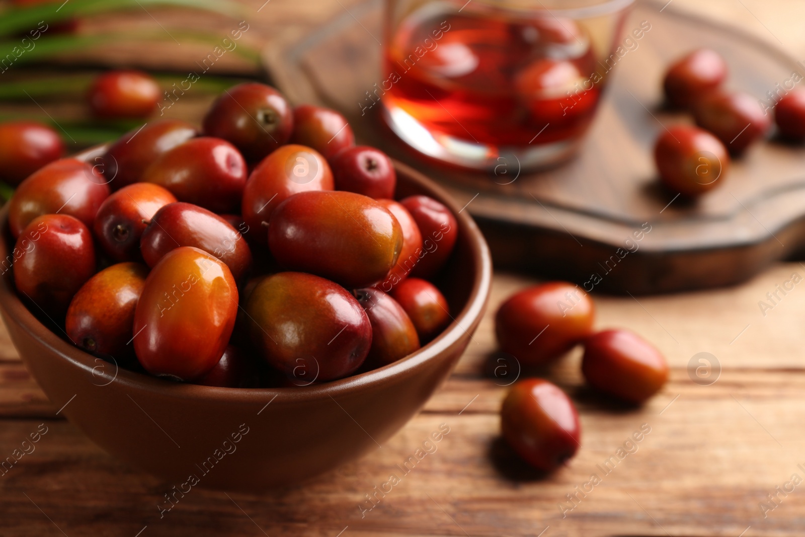 Photo of Palm oil fruits in bowl on wooden table, closeup