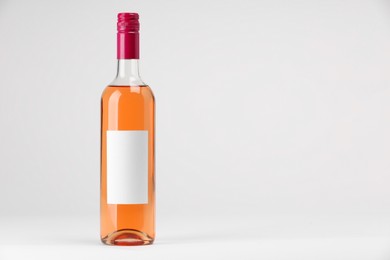 Bottle of tasty rose wine on white background, space for text