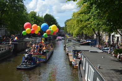 Photo of AMSTERDAM, NETHERLANDS - AUGUST 06, 2022: Many people in boats at LGBT pride parade on river