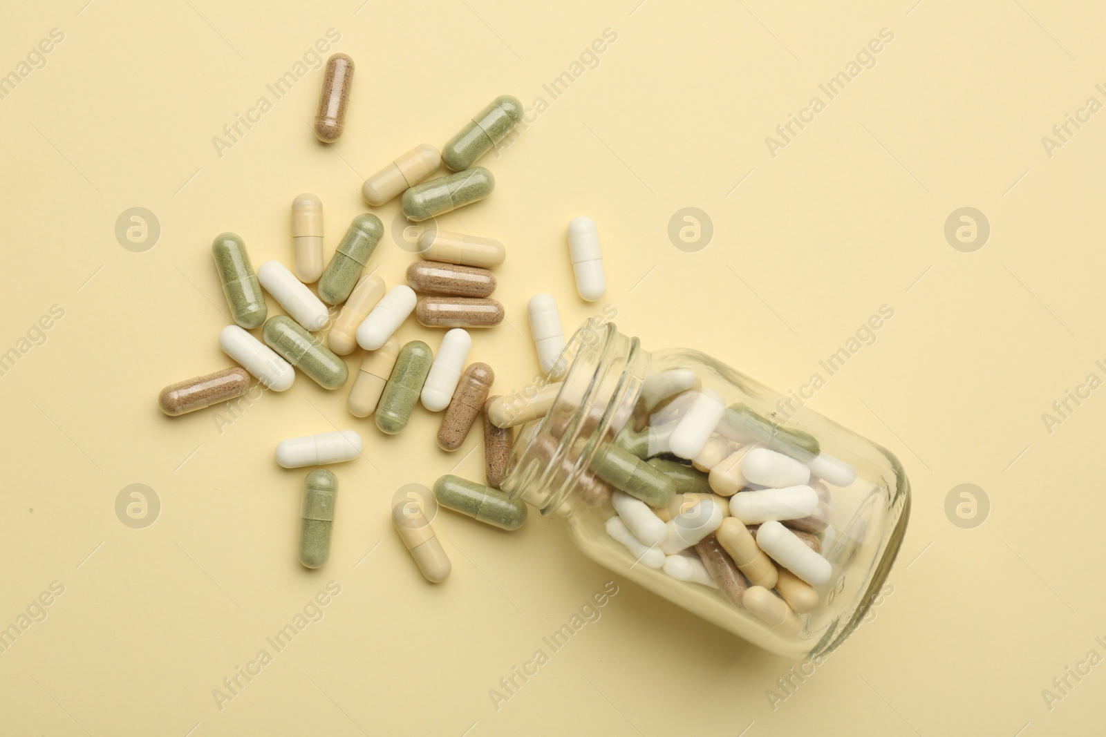 Photo of Vitamin pills and bottle on beige background, top view