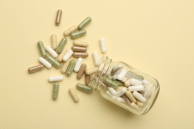 Photo of Vitamin pills and bottle on beige background, top view