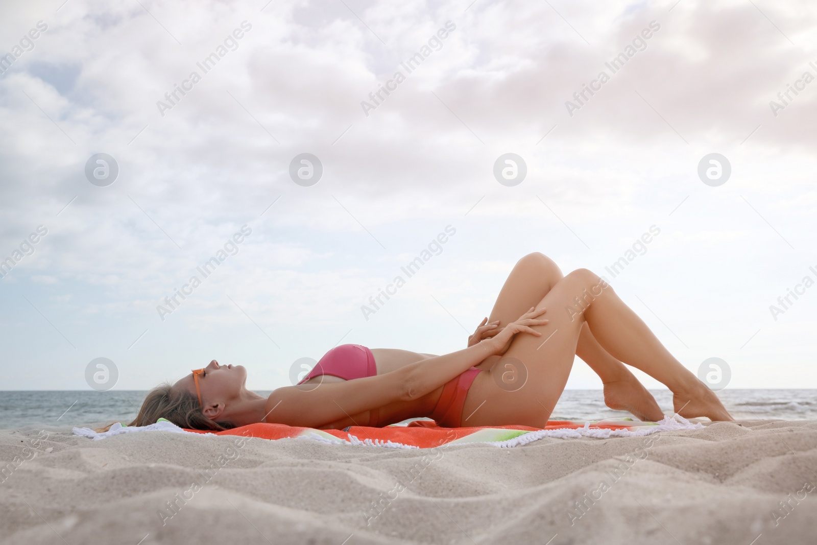 Photo of Beautiful woman lying on beach towel near sea