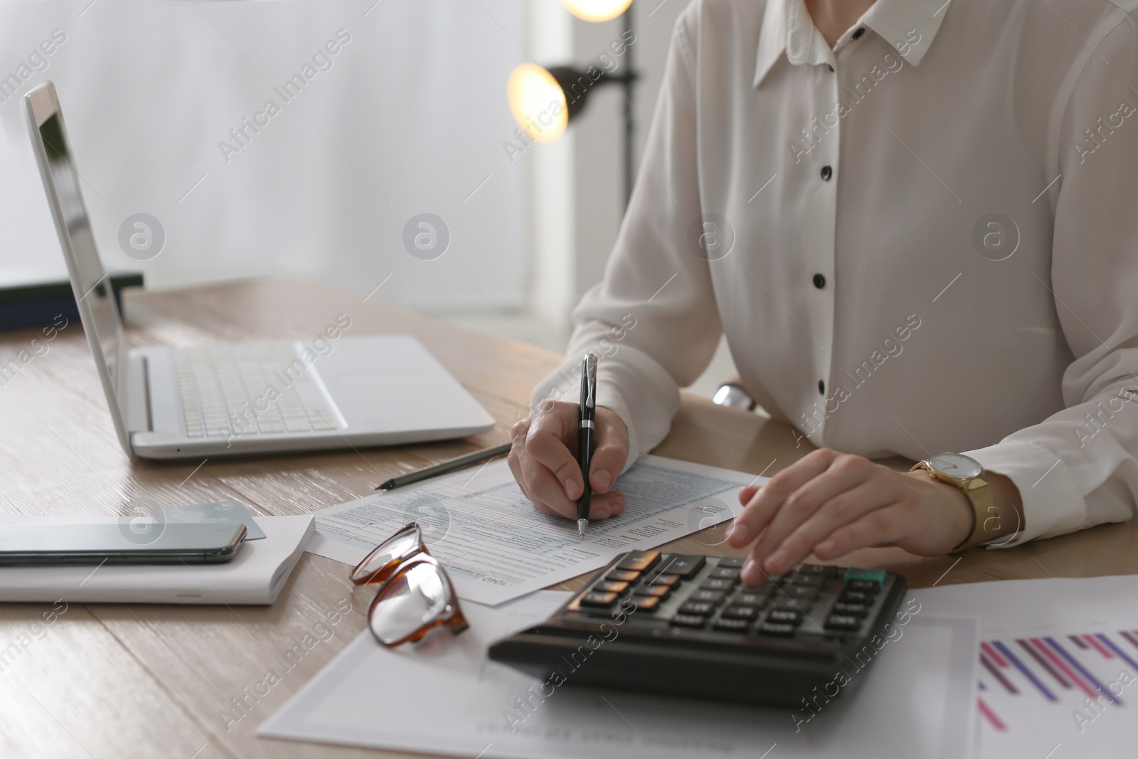 Photo of Tax accountant with calculator working at table in office, closeup