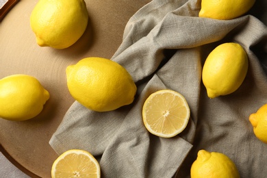 Photo of Flat lay composition with lemons, fabric and golden plate, closeup