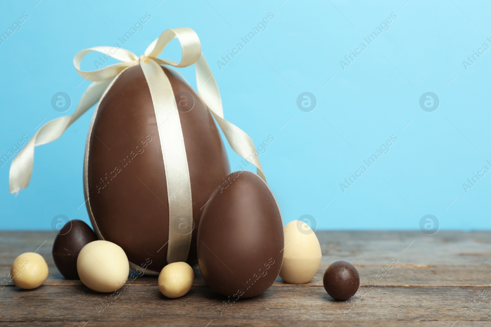 Photo of Composition with chocolate Easter eggs on table against color background. Space for text