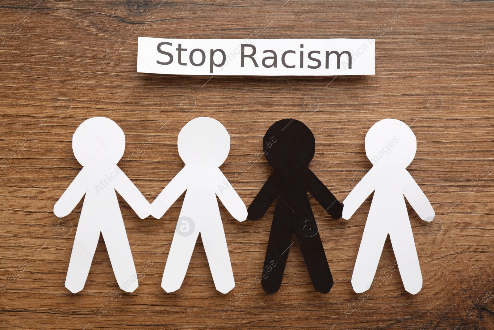 Photo of Phrase Stop Racism and paper figures on wooden table, flat lay