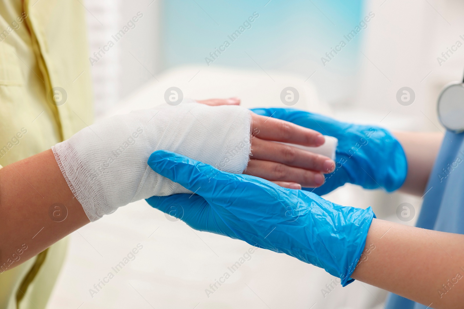 Photo of Doctor bandaging patient's burned hand indoors, closeup