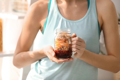 Young woman in fitness clothes with healthy breakfast at home, closeup