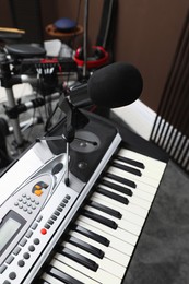 Photo of Modern synthesizer with microphone at recording studio. Music band practice