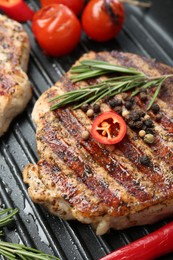 Photo of Delicious pork steak, spices and vegetables on grill pan, closeup