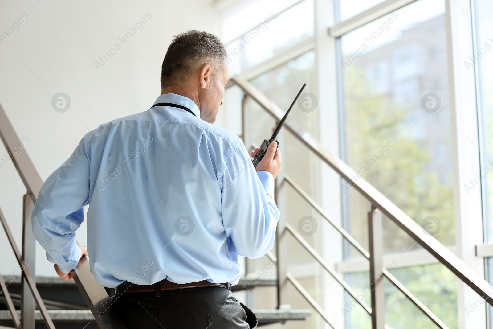 Photo of Male security guard using portable radio transmitter indoors