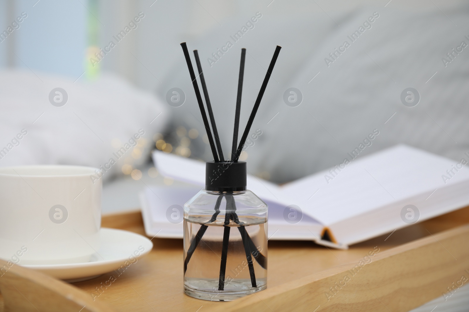 Photo of Aromatic reed air freshener on wooden tray in bedroom