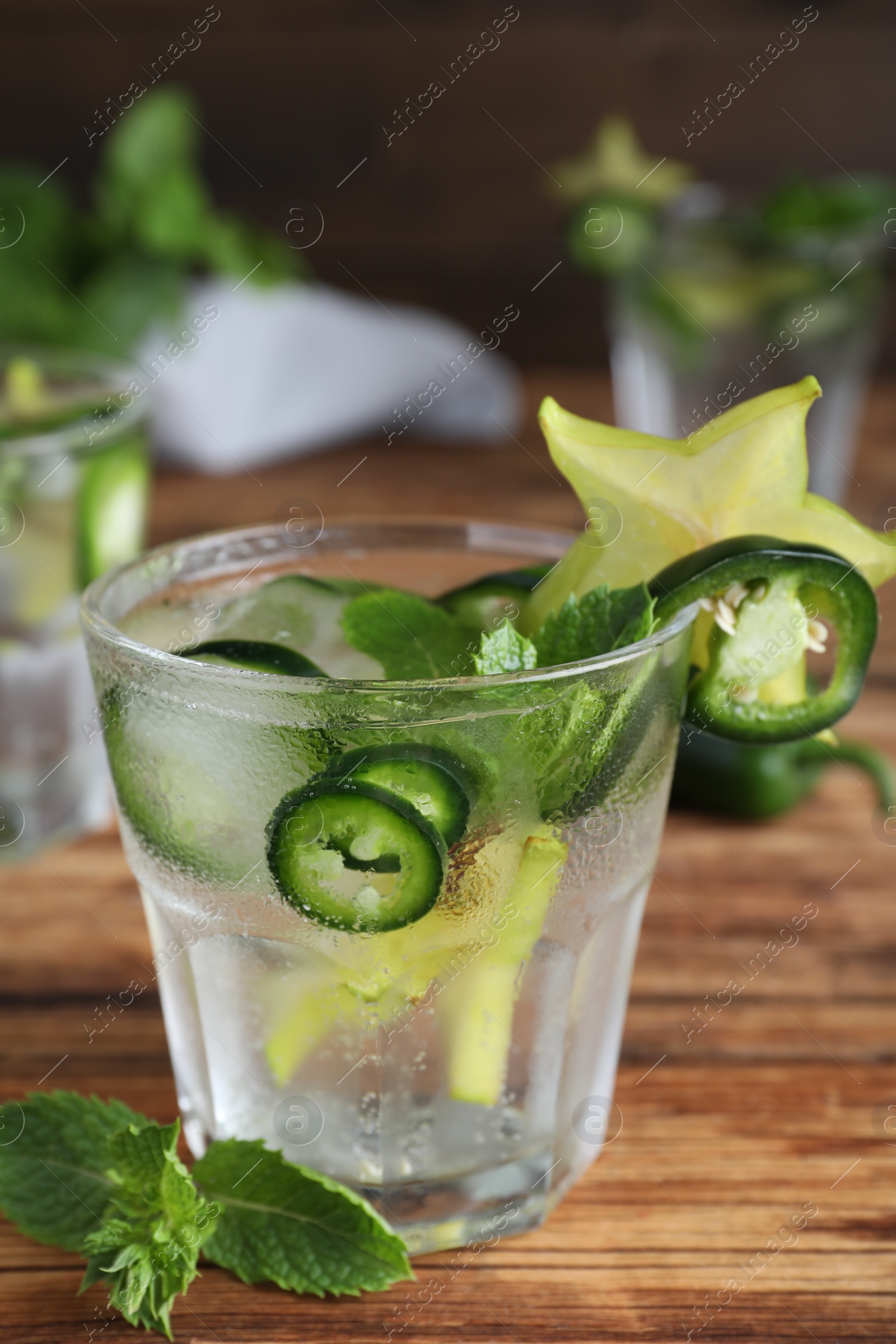 Photo of Spicy cocktail with jalapeno, carambola and mint on wooden table
