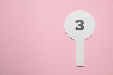 Photo of Auction paddle with number 3 on pink background, top view. Space for text