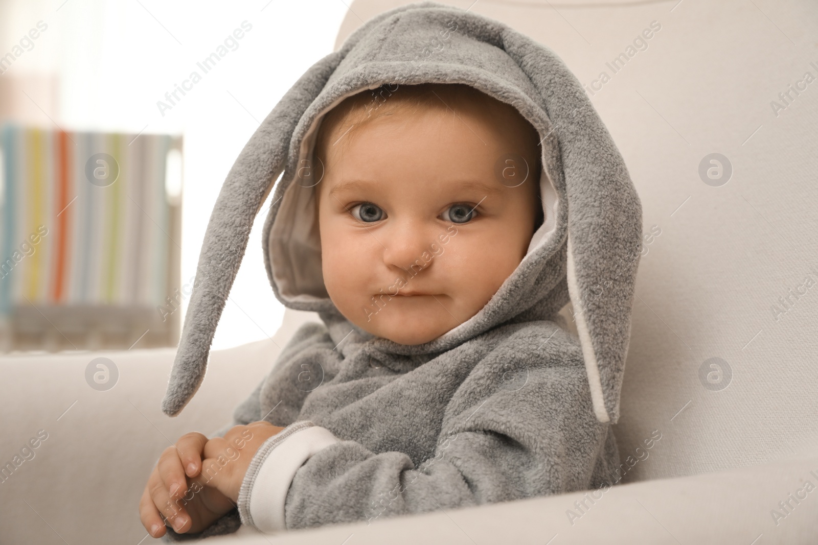 Photo of Cute little baby in funny suit with bunny ears indoors