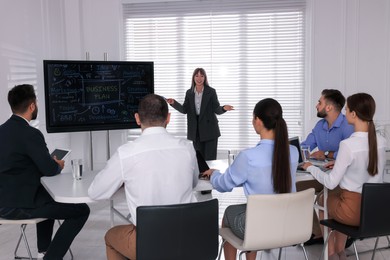Photo of Business trainer near interactive board in meeting room during presentation