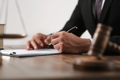 Photo of Law and justice. Closeup of judge working at wooden table near gavel