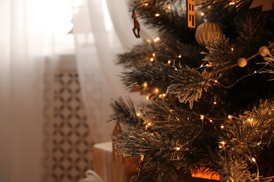 Beautiful decorated Christmas tree with fairy lights in room, closeup