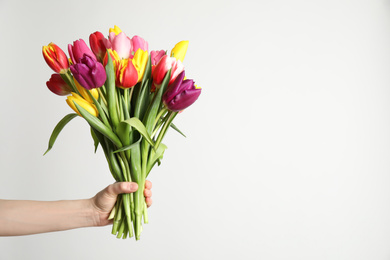 Photo of Woman holding beautiful spring tulips on white background, closeup. Space for text