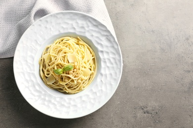 Photo of Plate of delicious basil pesto pasta on grey background, top view with space for text