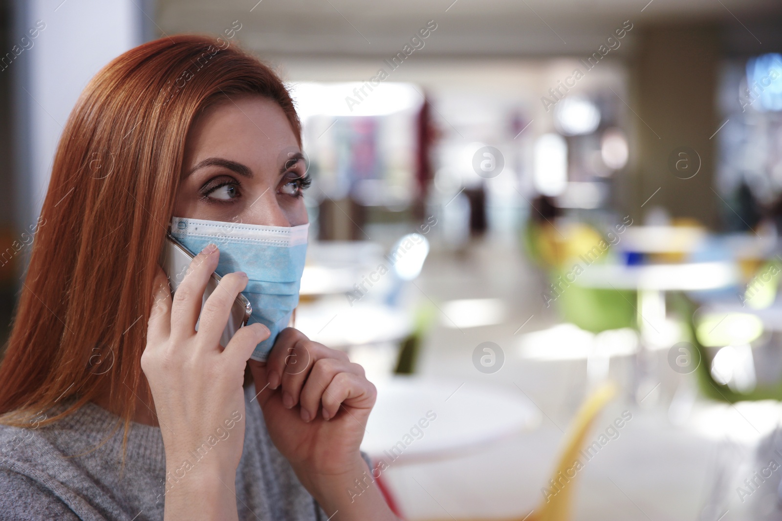 Photo of Woman with medical mask talking on mobile phone in cafe. Virus protection