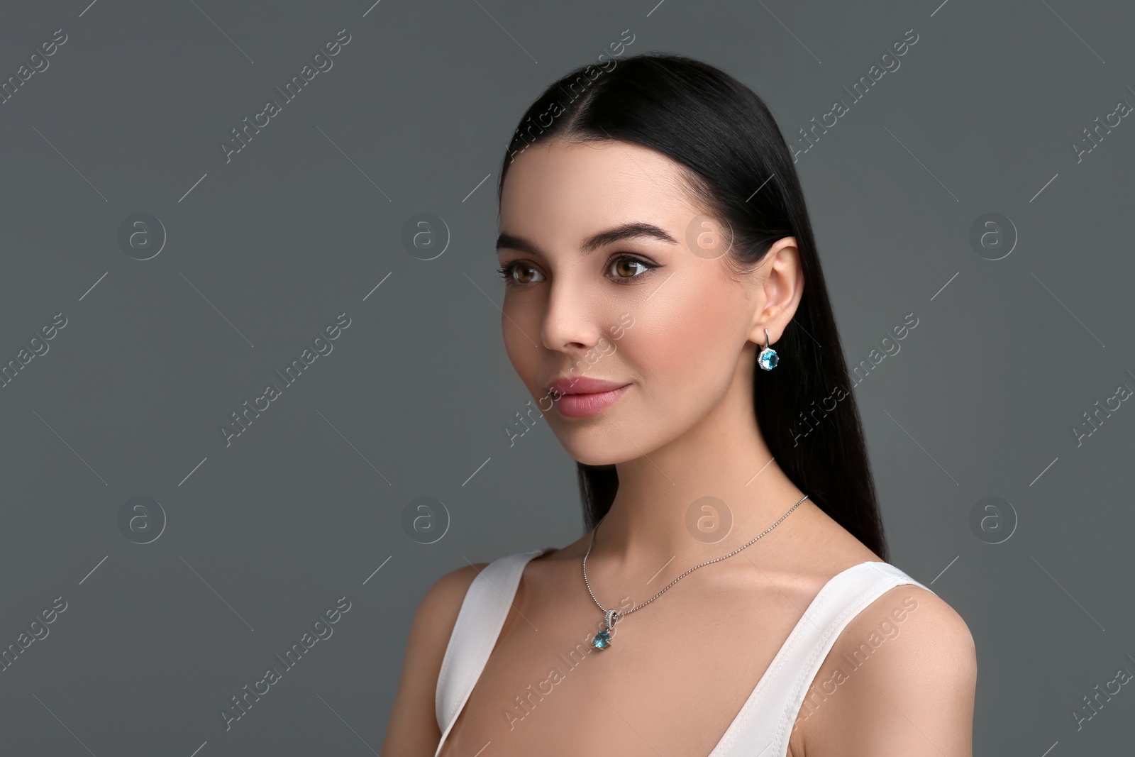 Photo of Beautiful young woman with elegant jewelry on dark grey background