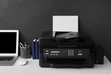 Photo of New modern printer, laptop and office supplies on white table