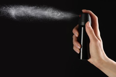 Image of Woman using pepper spray on black background, closeup