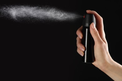 Woman using pepper spray on black background, closeup