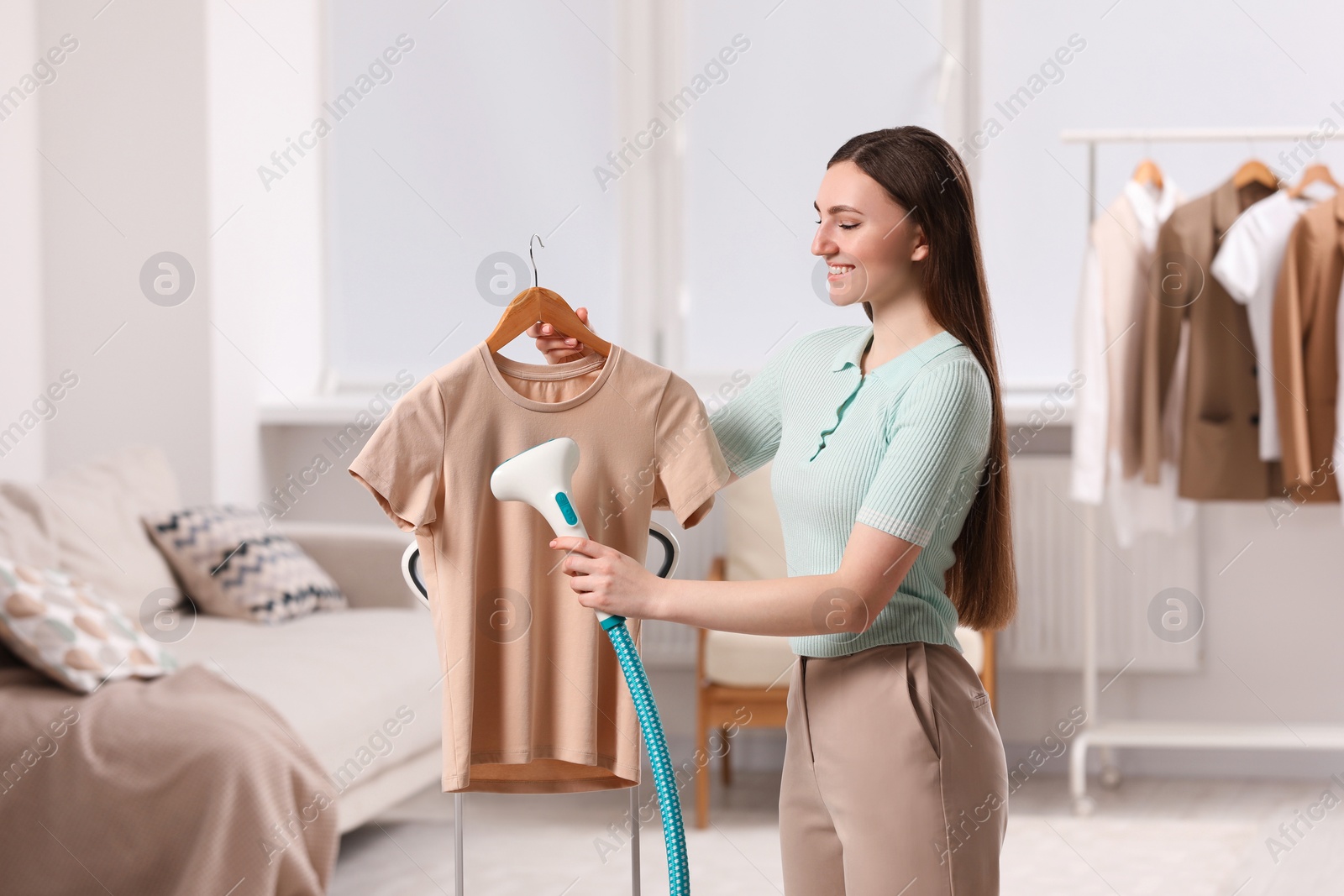 Photo of Woman steaming shirt on hanger at home