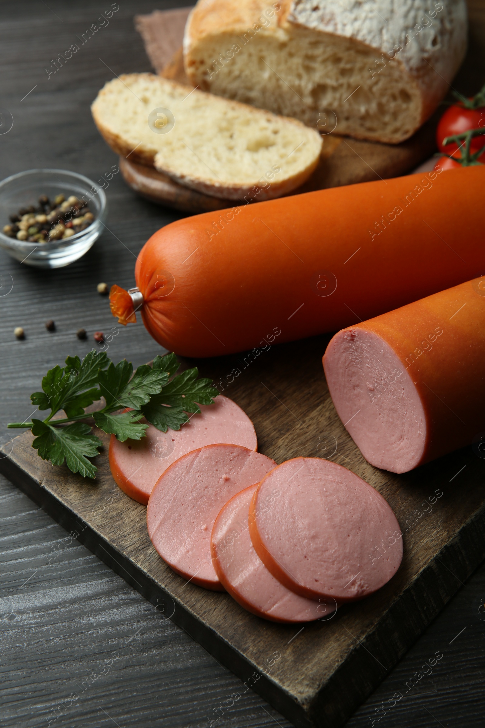 Photo of Board with tasty boiled sausages on dark wooden table