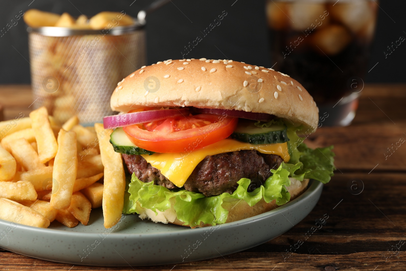 Photo of Delicious burger, soda drink and french fries served on wooden table, closeup