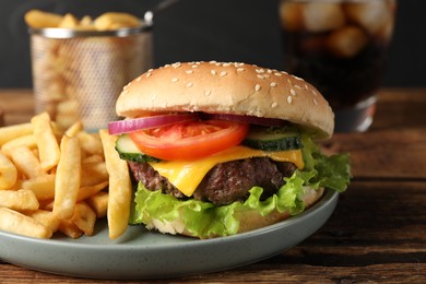 Photo of Delicious burger, soda drink and french fries served on wooden table, closeup