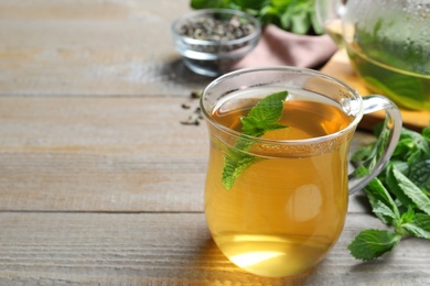 Photo of Cup with hot aromatic mint tea on wooden table, space for text