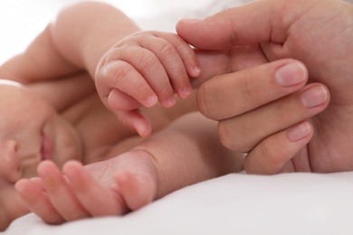 Photo of Mother with her cute baby on bed, closeup of hands