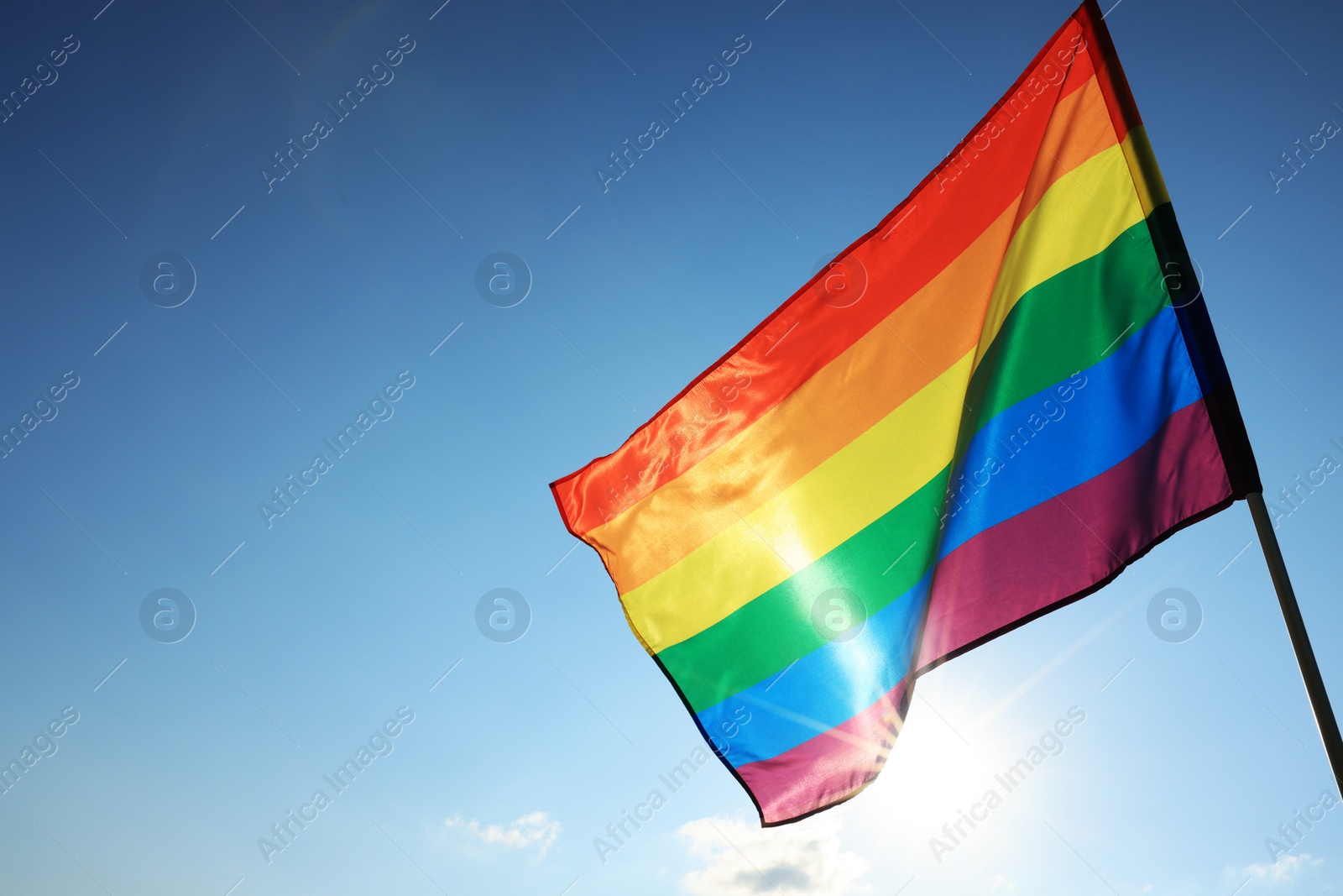 Photo of Bright LGBT flag fluttering against blue sky, space for text. Lesbian concept