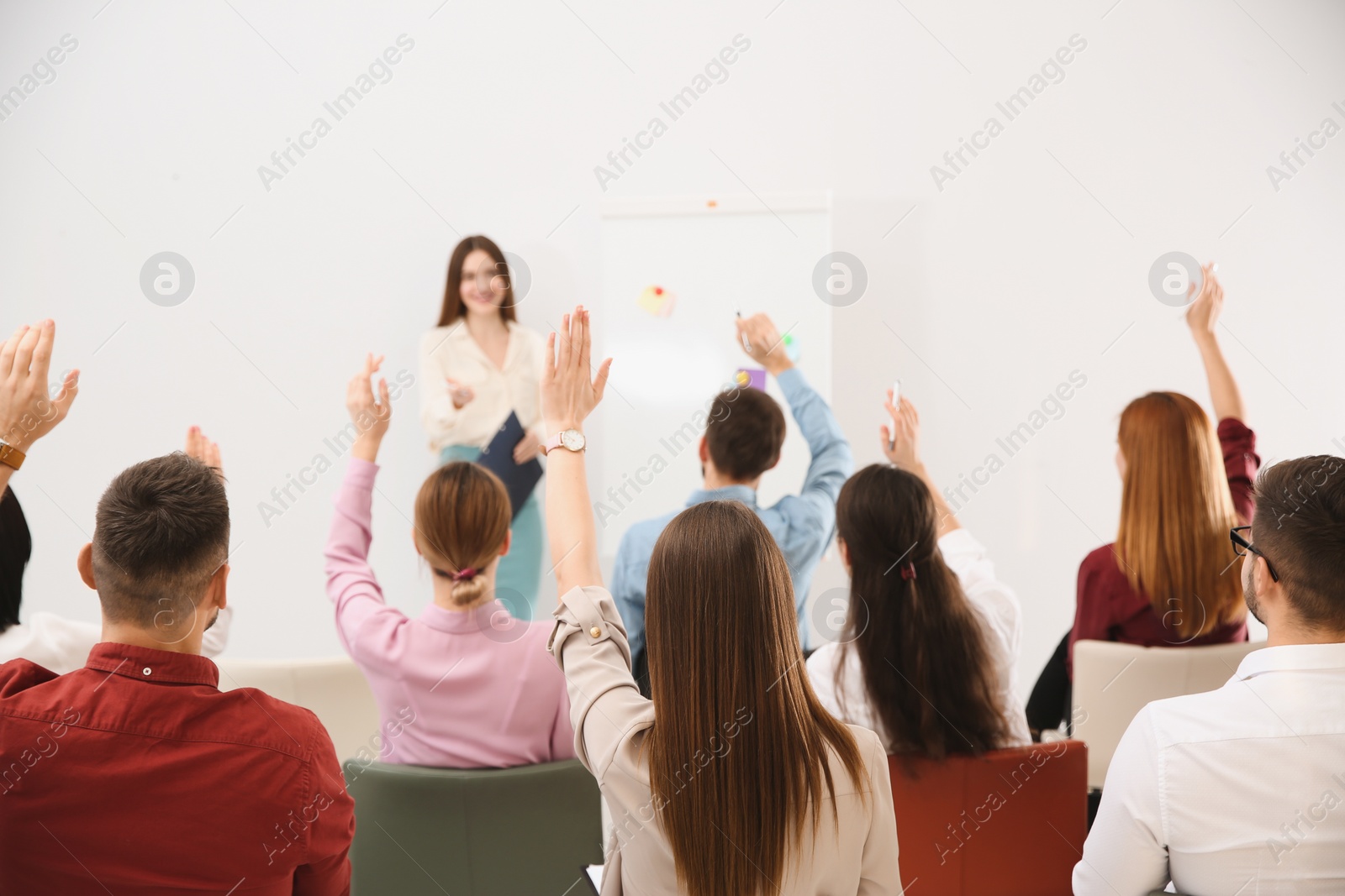 Photo of People raising hands to ask questions at business training indoors