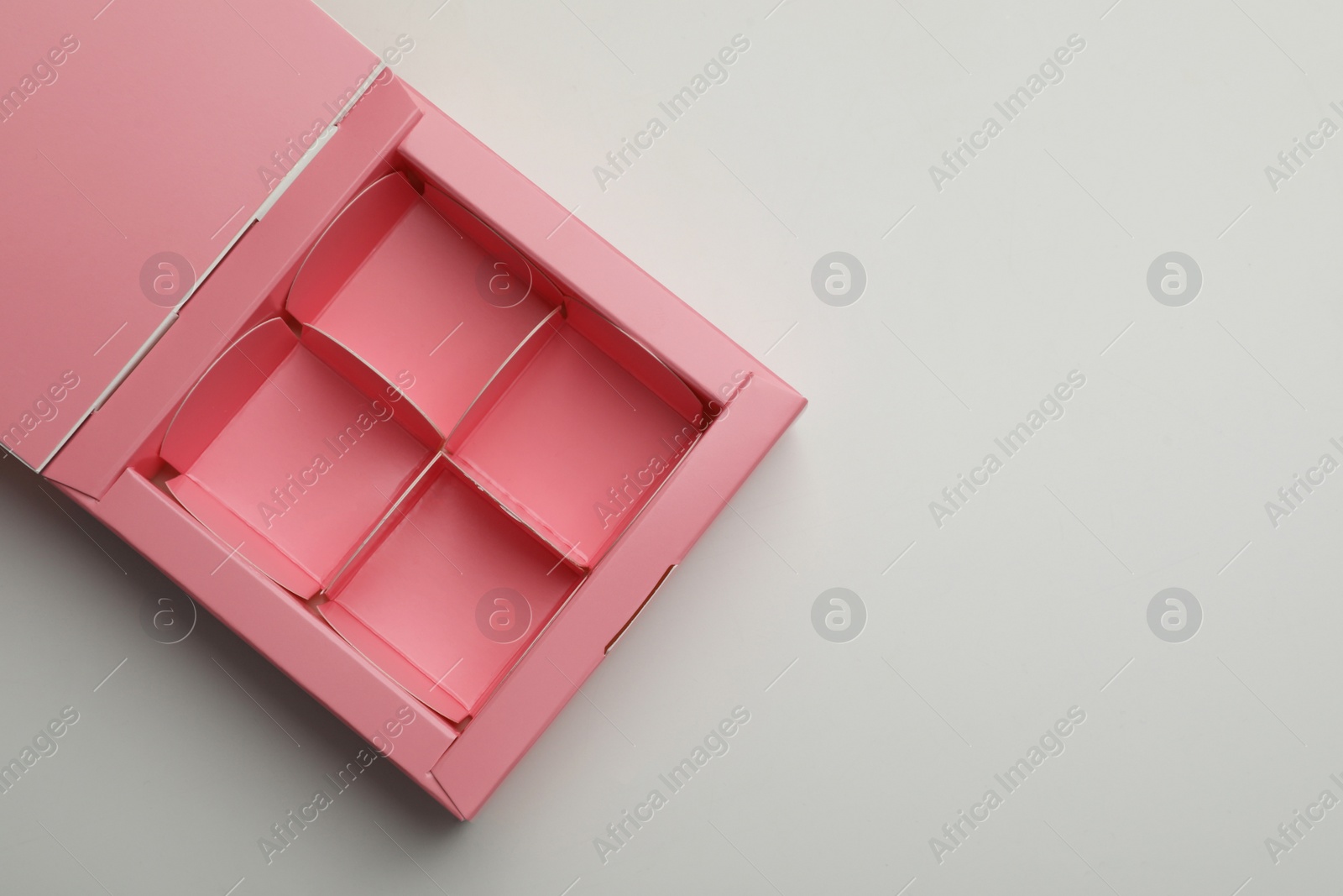 Photo of Empty pink candy box on light grey background, top view. Space for text