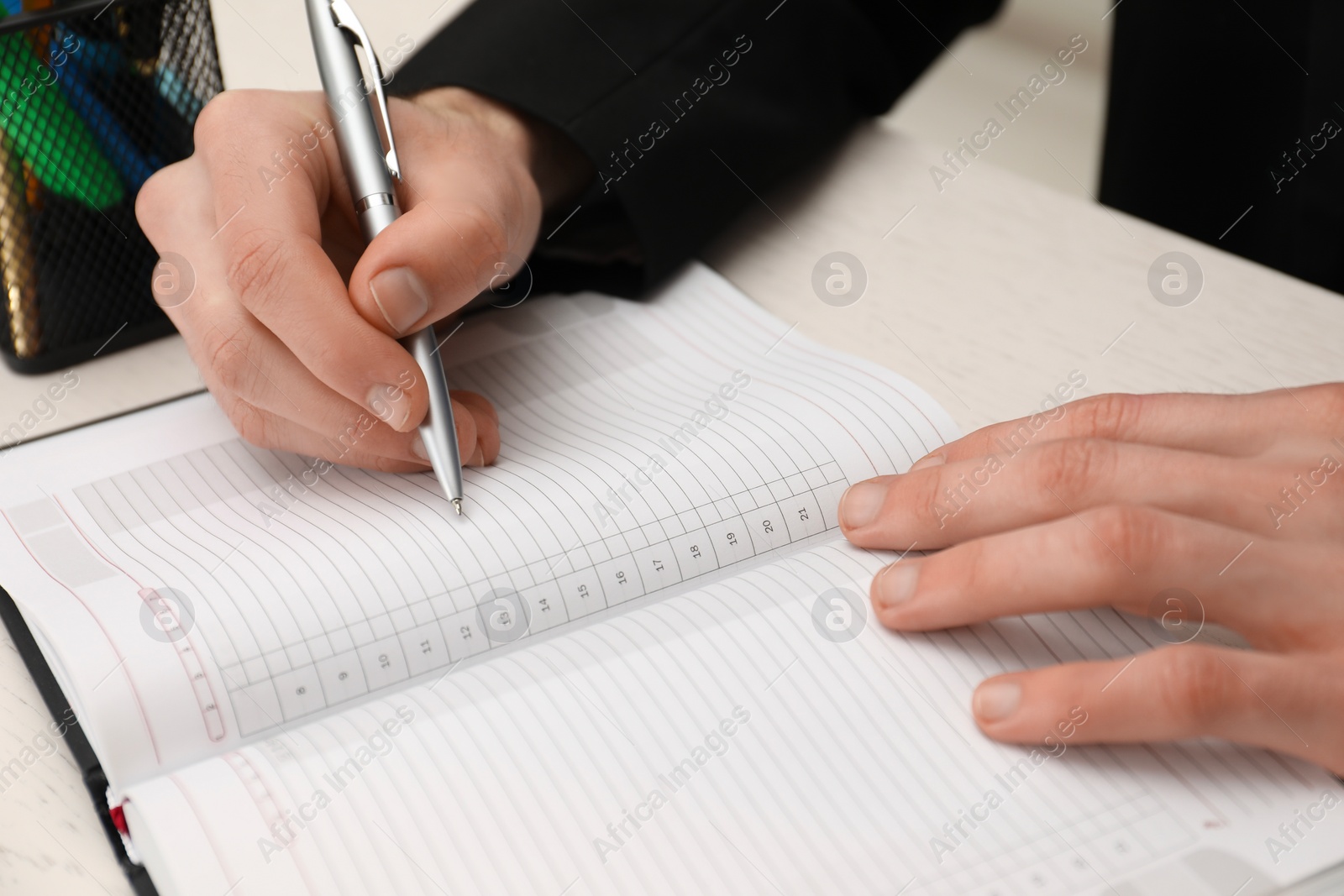 Photo of Man taking notes at white wooden table, closeup