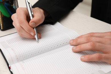 Photo of Man taking notes at white wooden table, closeup