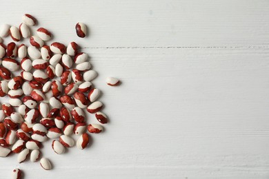 Raw beans and space for text on white wooden background, flat lay. Vegetable seeds