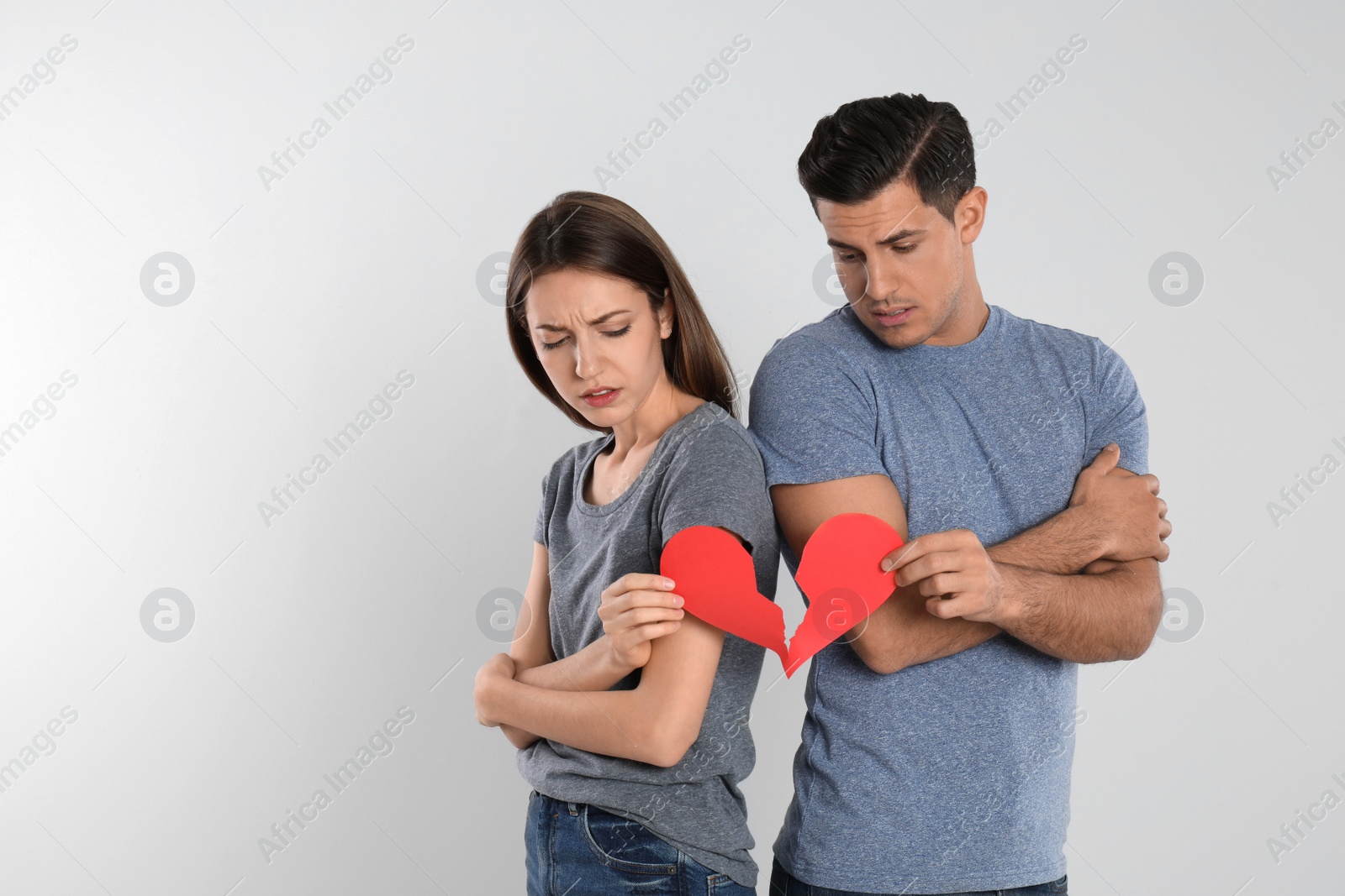 Photo of Couple with torn paper heart on light background. Relationship problems