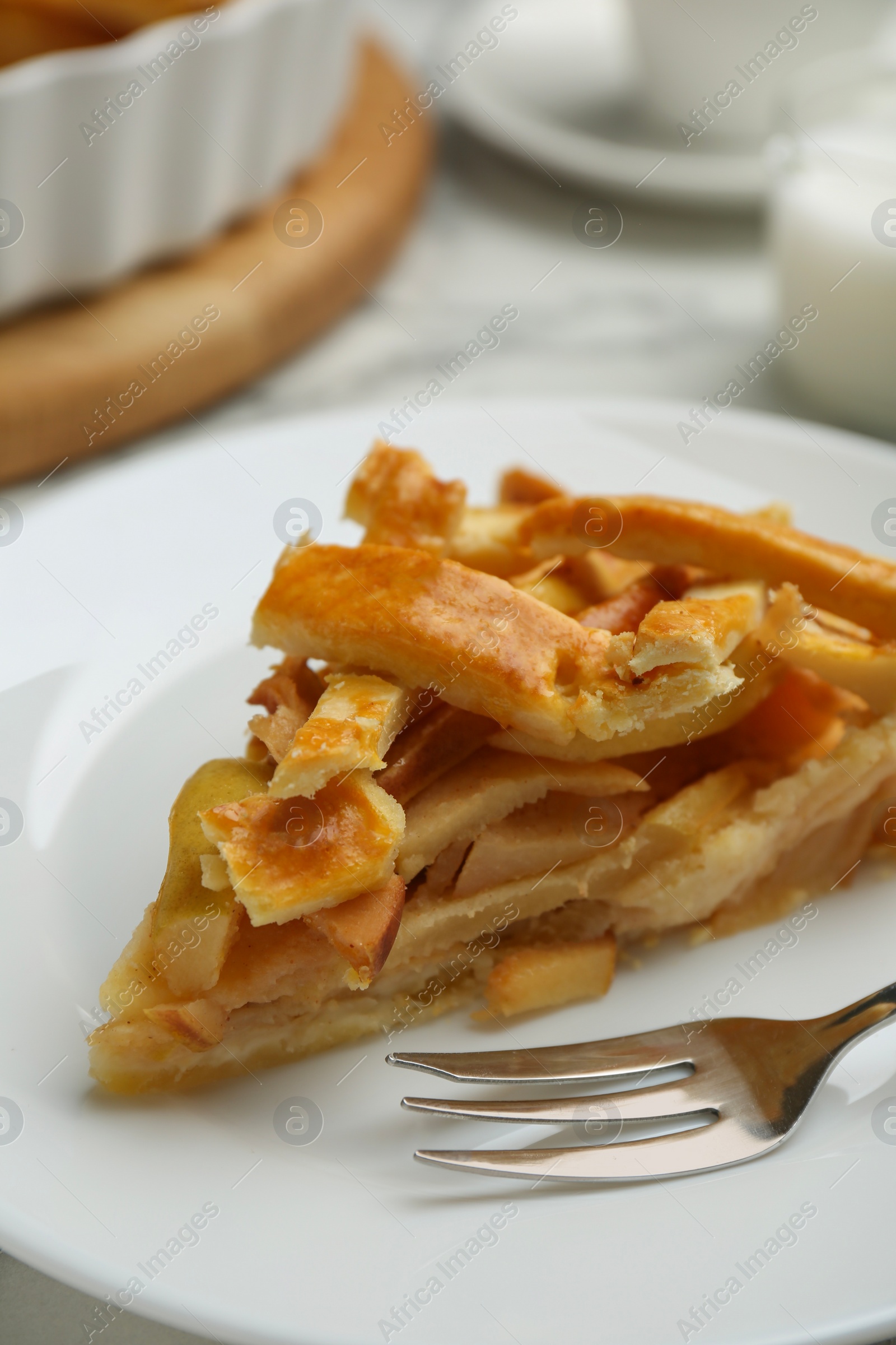Photo of Piece of tasty homemade quince pie and fork on white table, closeup