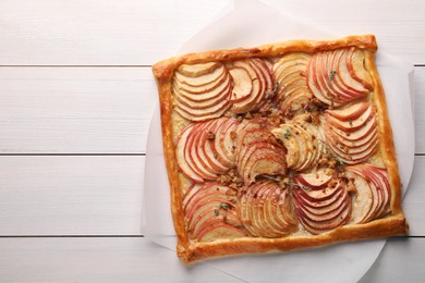 Photo of Freshly baked apple pie with nuts on white wooden table, top view. Space for text