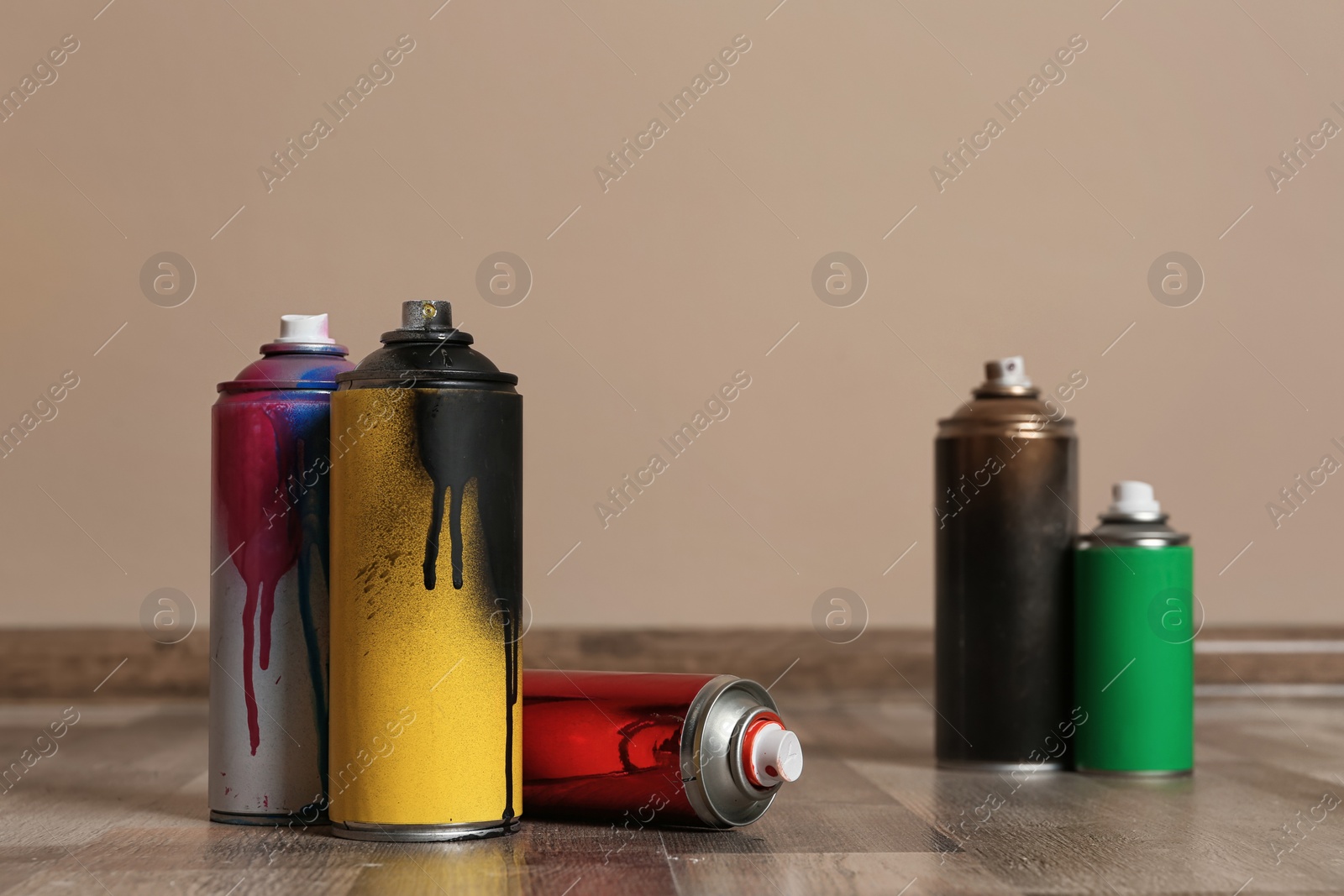 Photo of Used cans of spray paint on floor indoors. Space for text