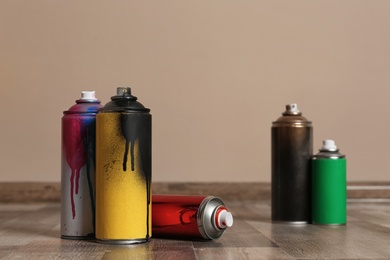 Photo of Used cans of spray paint on floor indoors. Space for text